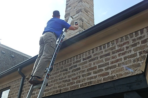 home inspector on ladder, inspecting roof